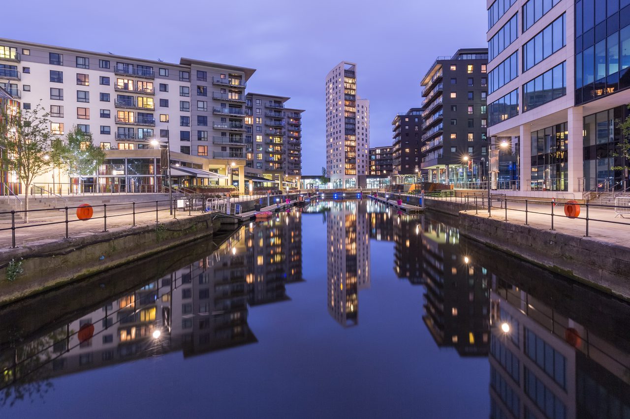 Leeds Clarence Dock at dusk, with apartment buildings and a tower reflected in the still water.