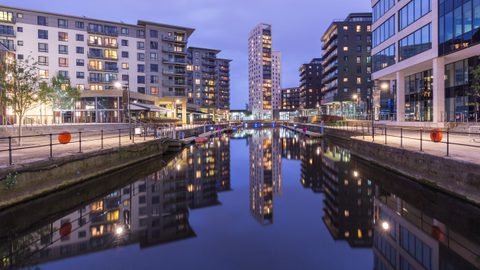 Leeds Clarence Dock at dusk, with apartment buildings and a tower reflected in the still water.