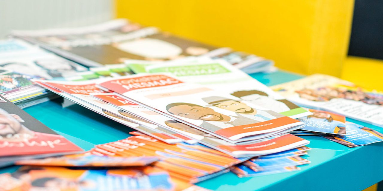 A teal table covered with stacks of Yorkshire MESMAC sexual health leaflets and booklets.