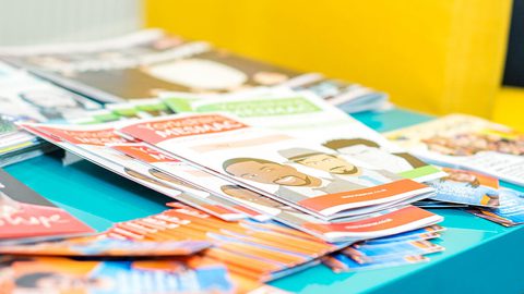 A teal table covered with stacks of Yorkshire MESMAC sexual health leaflets and booklets.