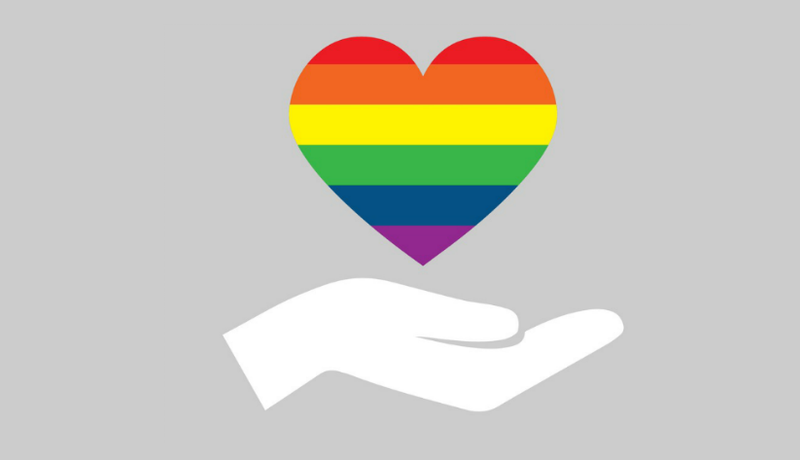 Illustration of a hand holding a rainbow-striped heart on a grey background.