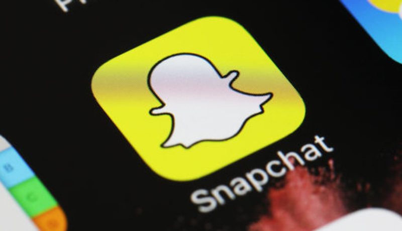 Close-up of a phone screen showing the Snapchat app icon among other apps.